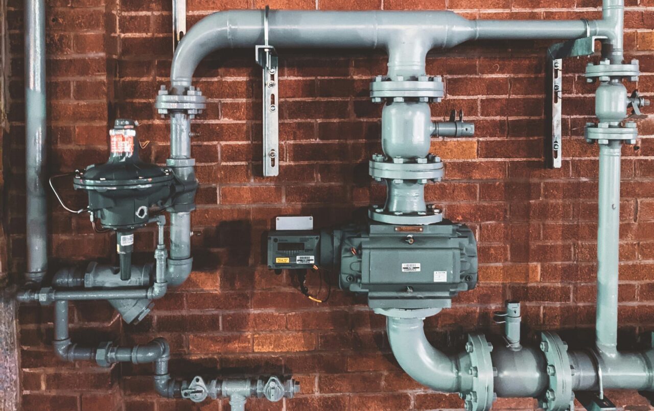 Commercial water line with backflow preventer mounted on a brick wall